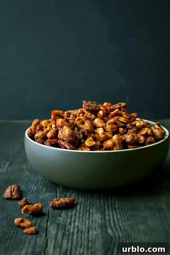 Sweet and spicy roasted nuts in a large green bowl on a wooden table.