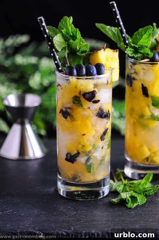 Blueberry pineapple mojitos garnished with blueberry and pineapple chunks.