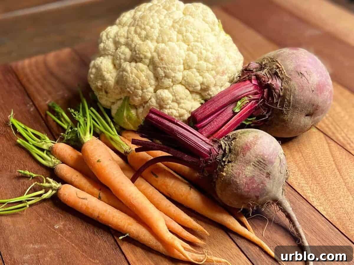 Carrots, cauliflower, and beets on a chopping board.