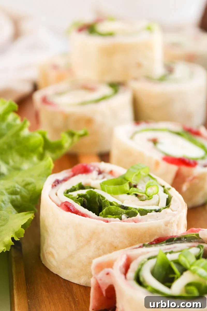 Cold Turkey and Cranberry Pinwheels for Leftovers 2 Cranberry turkey pinwheels on a wooden board.
