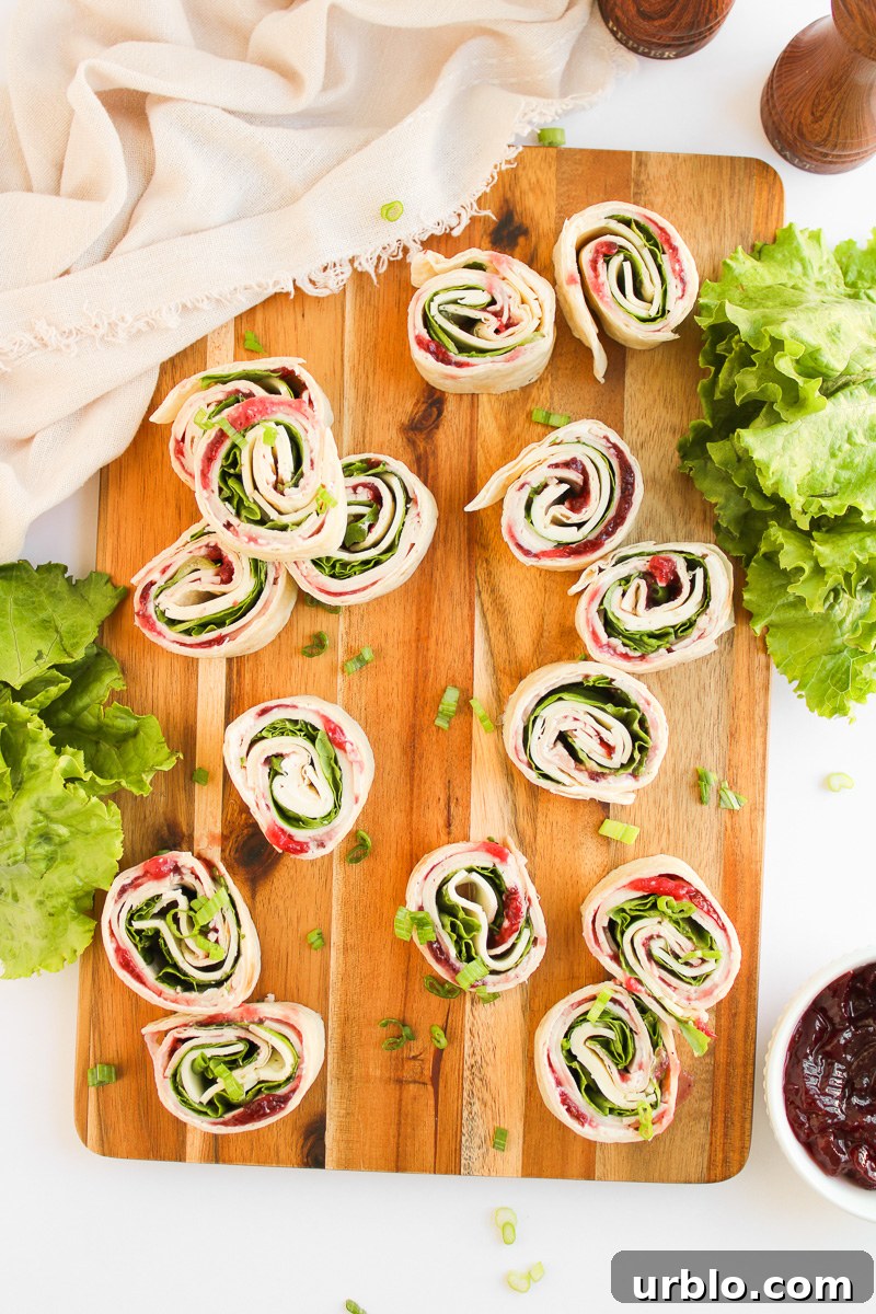 Cold Turkey and Cranberry Pinwheels for Leftovers 3 Overhead view of turkey cranberry pinwheels on a wooden board.