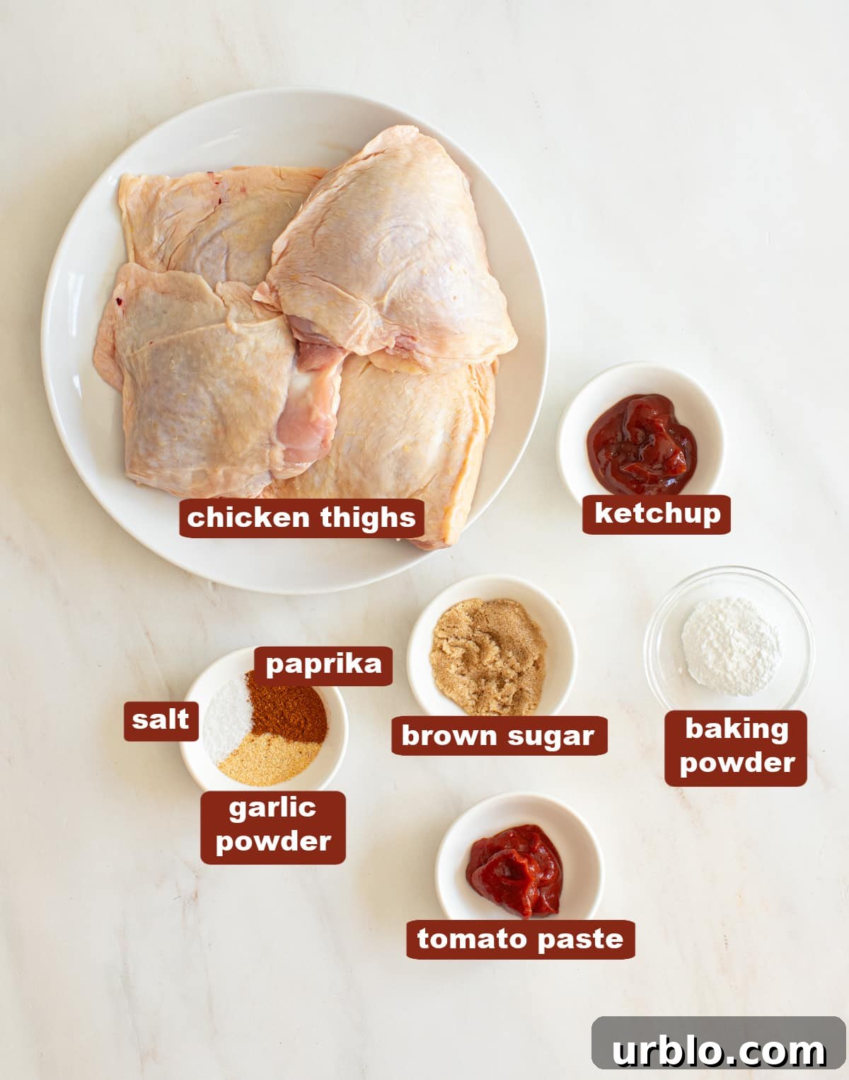 All of the ingredients for air fryer chicken thighs in bowls on a white countertop. 