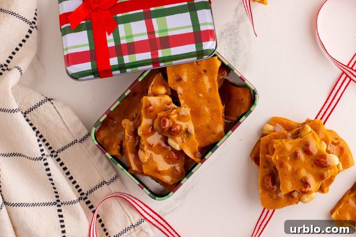 Classic Old-Fashioned Peanut Brittle Recipe 9 Broken peanut brittle pieces on parchment paper with a knife.