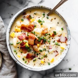 Sweetcorn chowder with bacon in a white bowl with herbs.