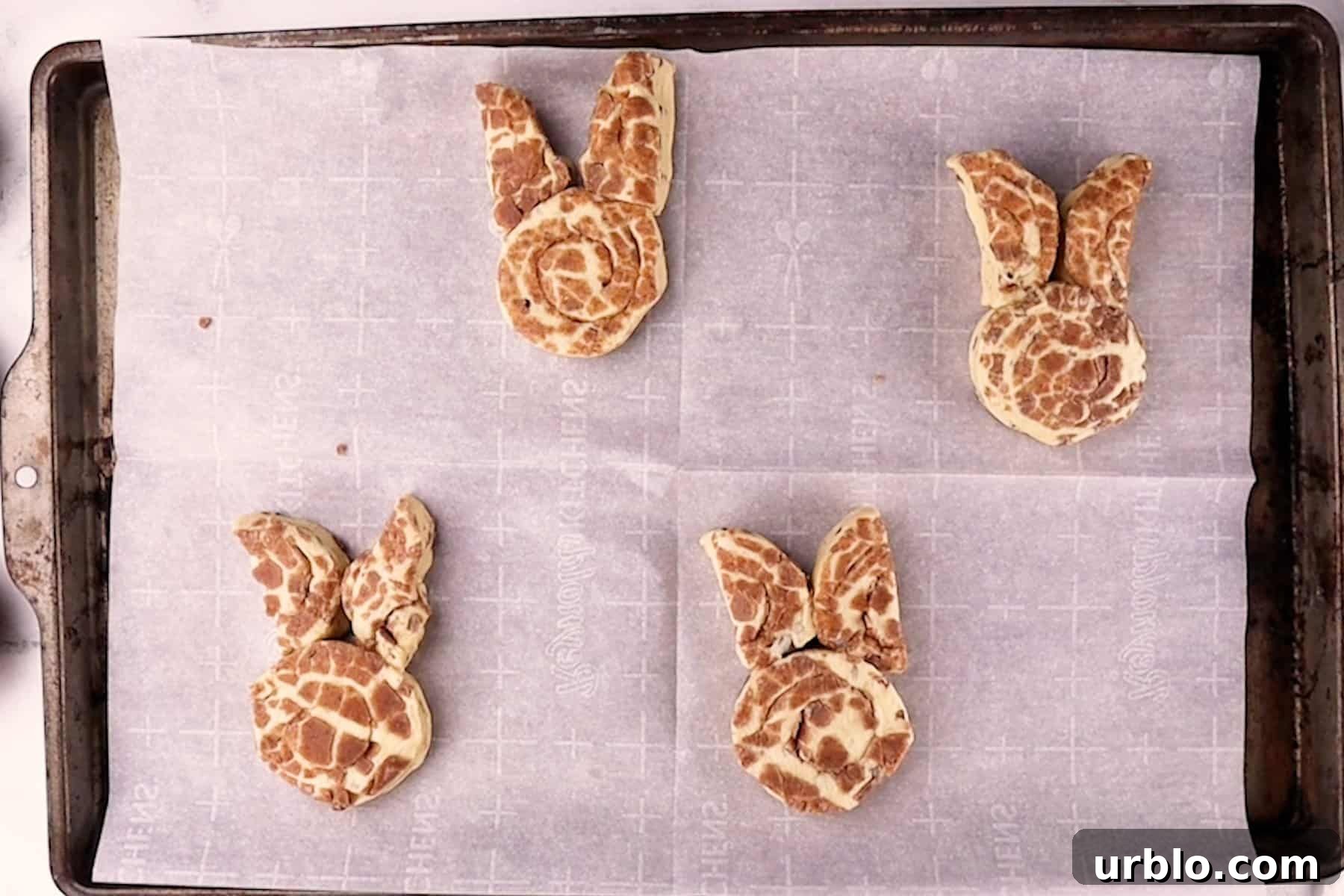bunny cinnamon rolls that don't unroll before baking, cut and shaped on a baking sheet.