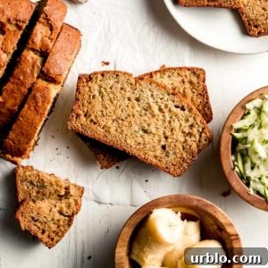 Gluten-free Zucchini Banana Bread sliced, laid on it's side, next to the rest of the loaf and a dish of zucchini and banana.