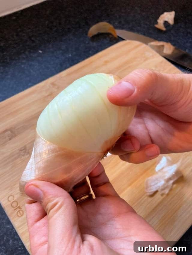 hand holding and onion pulling the peel off