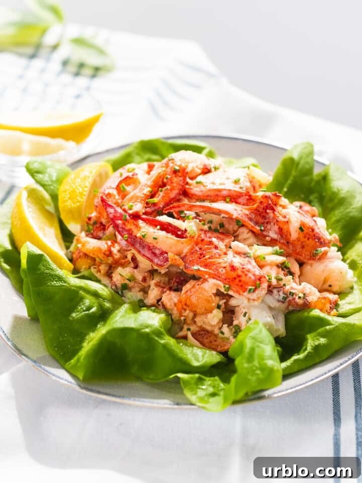 Lobster salad on top of lettuce next to lemons.
