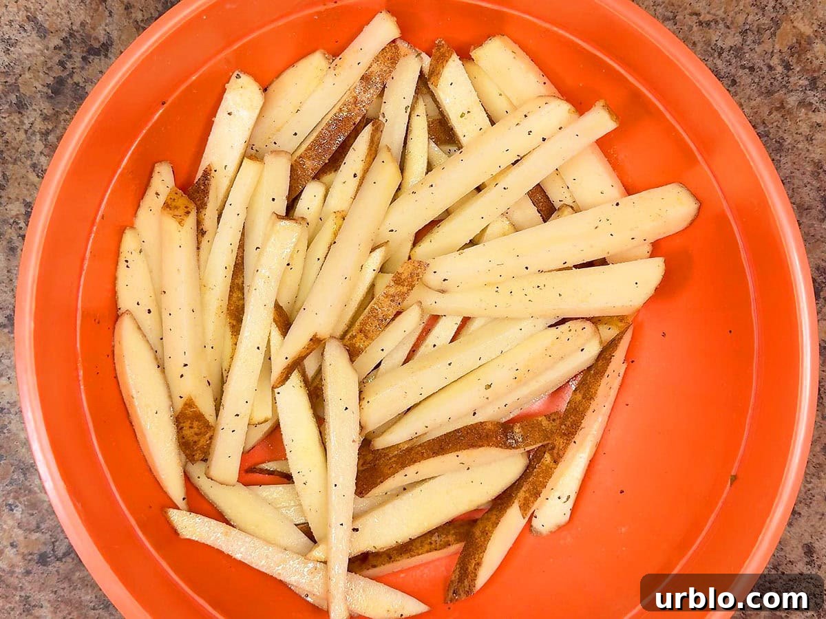 Oiled and seasoned cut potatoes in a large bowl.