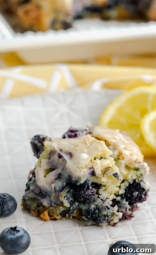 A slice of blueberry lemon bar using boxed cake mix with fresh blueberries on plate. 