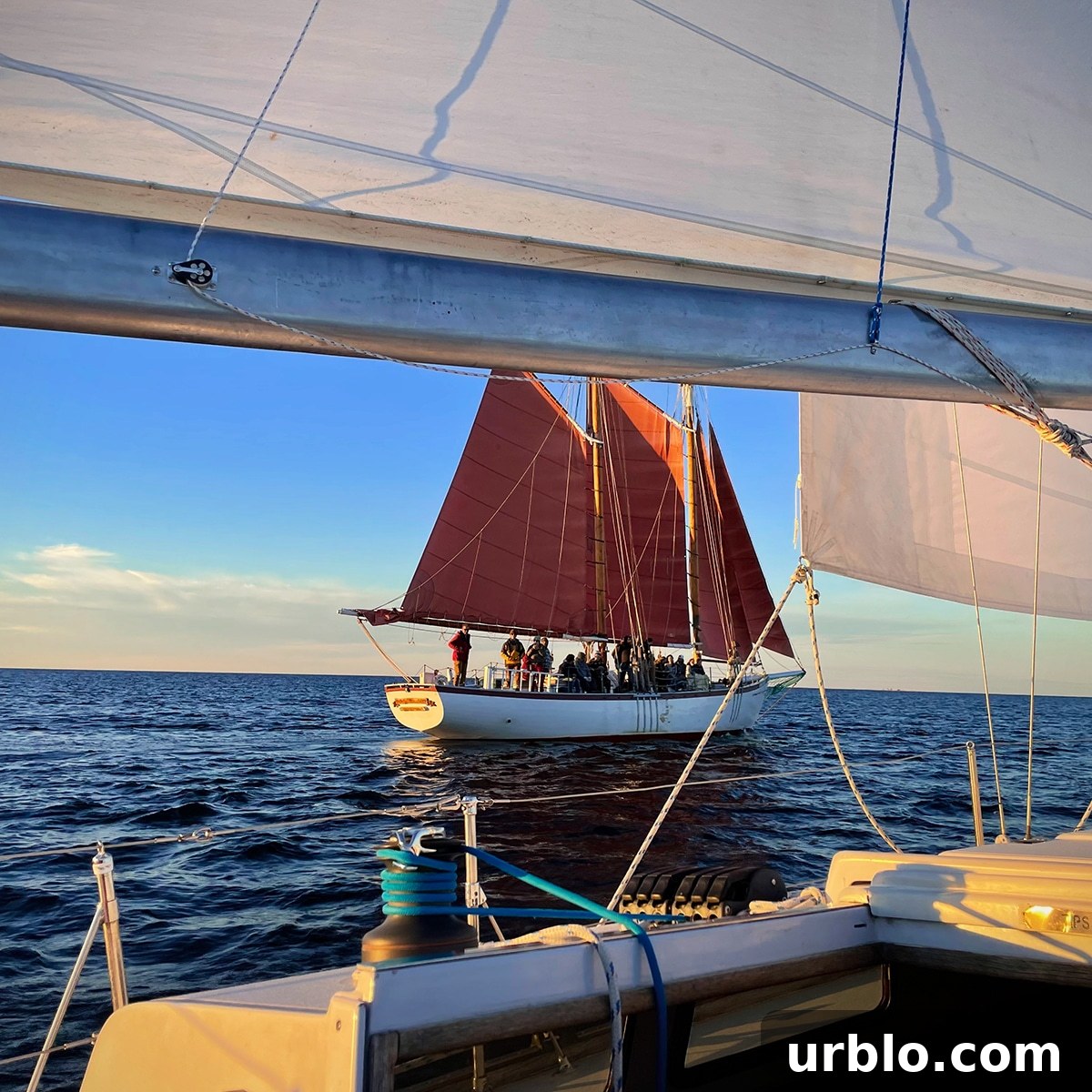 Looking at a Tall ship passing us by as we sail on a 40 foot sailboat at sunset.