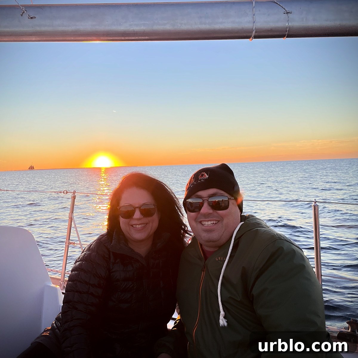 Steve and Rebecca Blackwell on a sailboat in Door County, Wisconsin with the sun setting in the background.