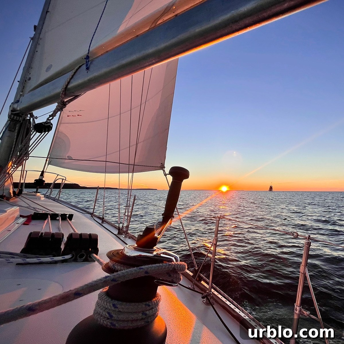 Looking towards the bow of a sailboat while sailing at sunset.
