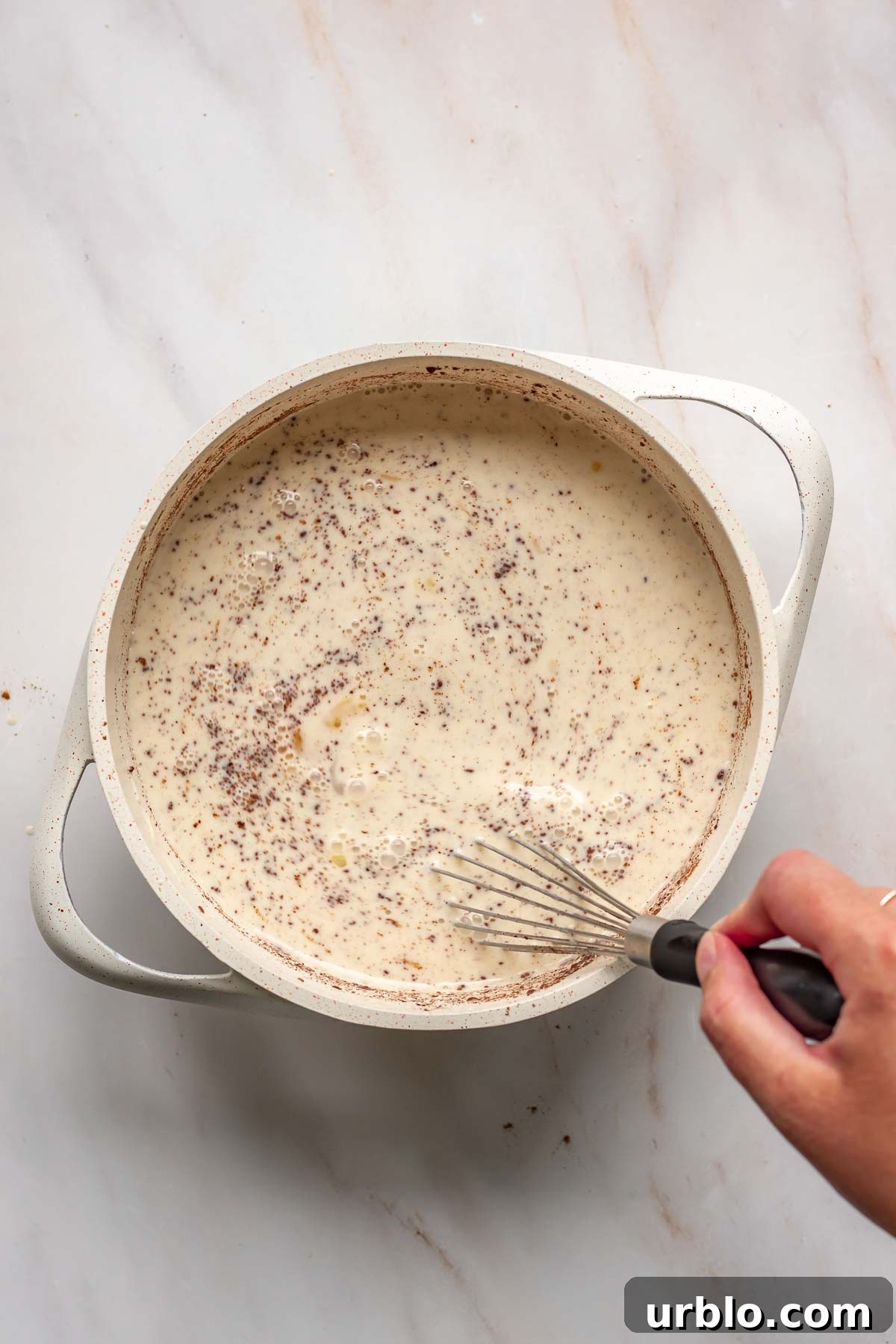 A hand whisks together cinnamon custard.