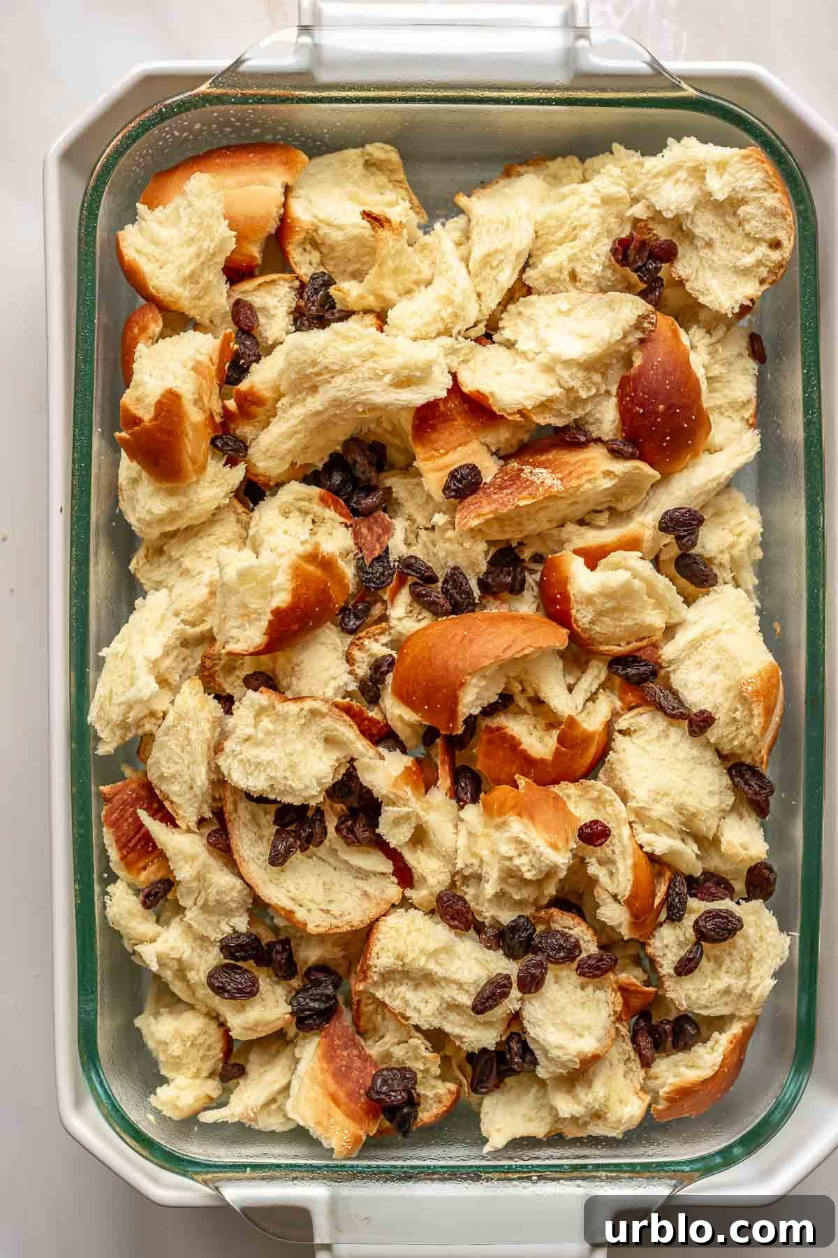 Raising and challah bread pieces in a casserole dish.