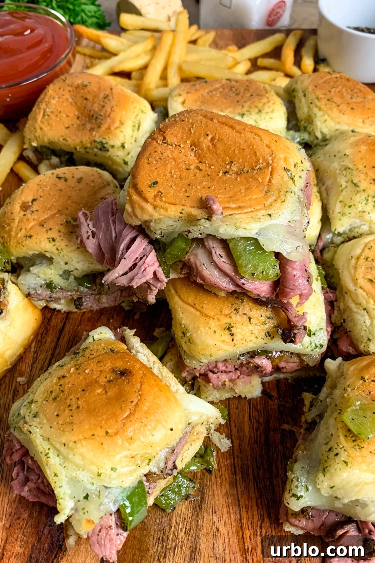 Cheesesteak sliders made with roast beef, onions, and green peppers stacked on top of each other.