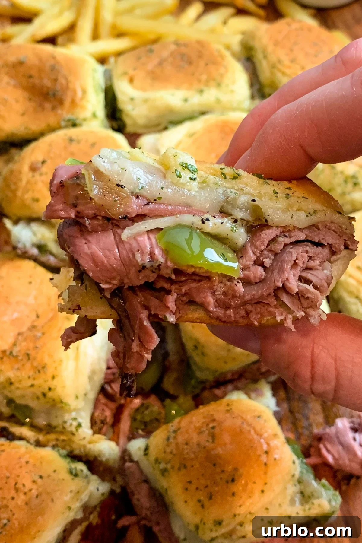 Close up of Philly cheesesteak sliders to show off the roast beef, cheese, and peppers.