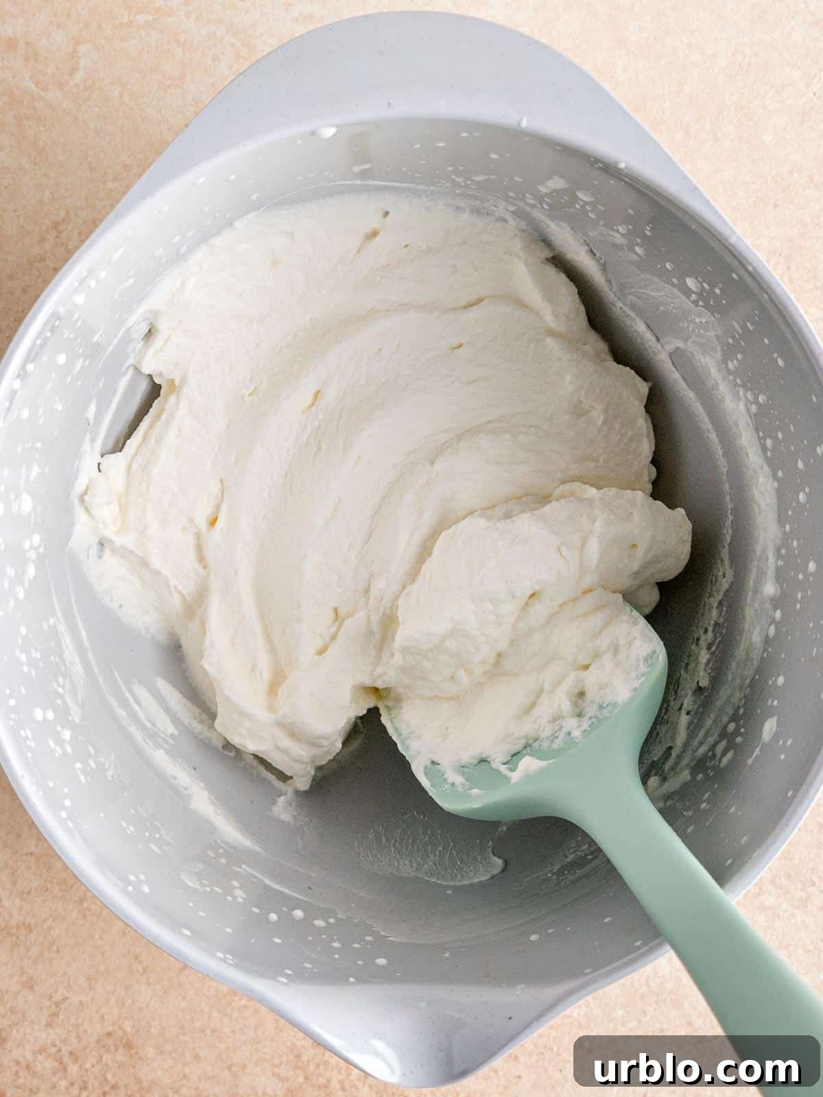 Whipped cream in a bowl with a spatula.