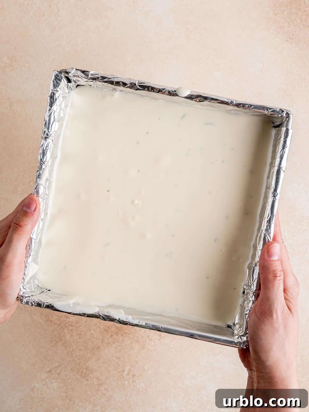 An 8-inch pan filled with graham cracker crust and key lime cheesecake.