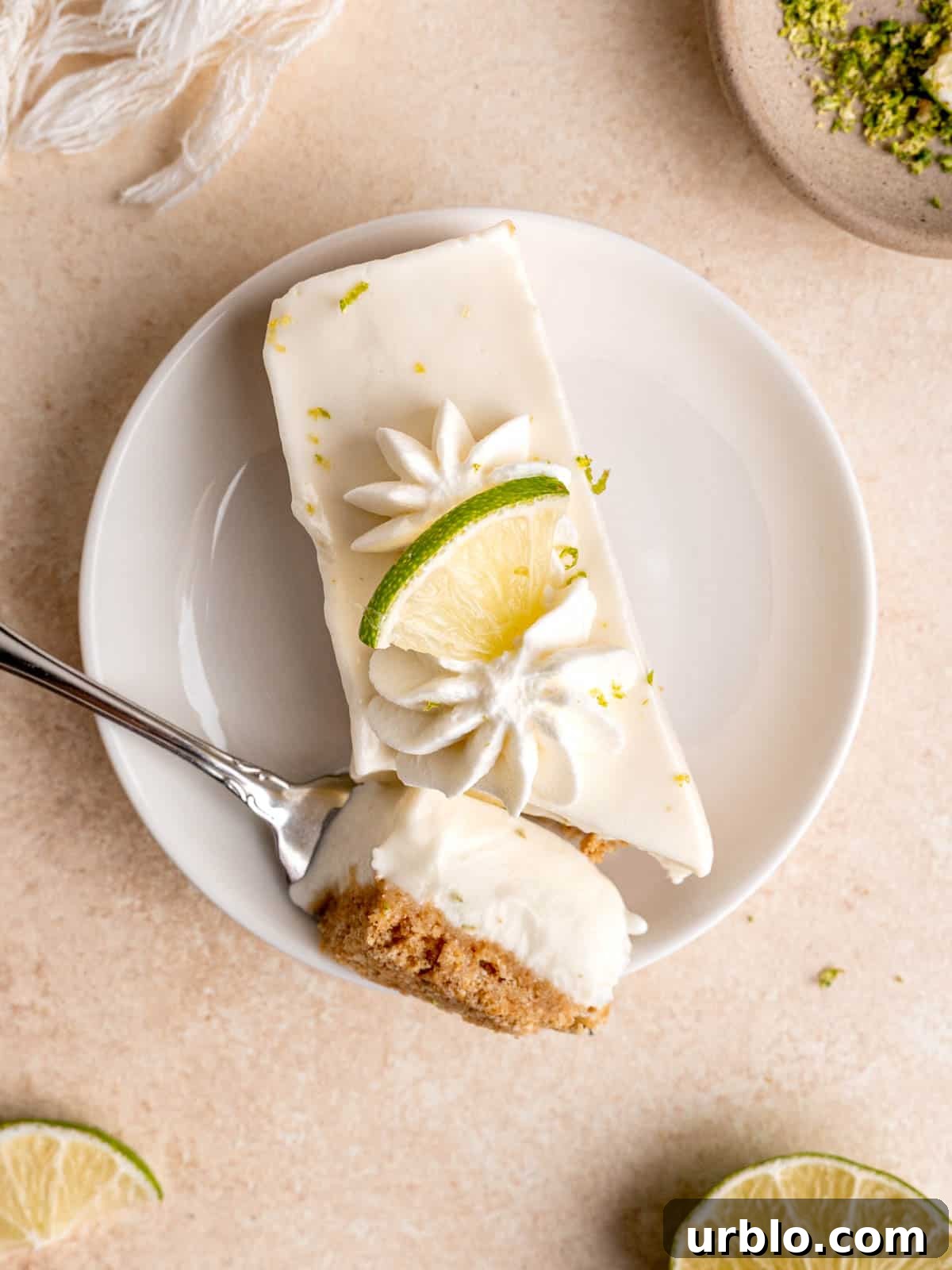 A creamy key lime cheesecake bar with a bite cut out of it.