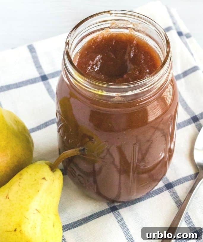 jar of pear butter on a blue and white npakin with two ripe pears next to it