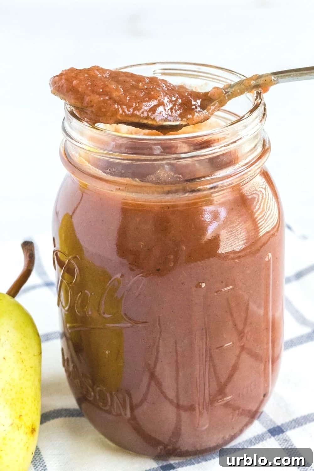 Ball jar of pear butter with a spoon resting on top