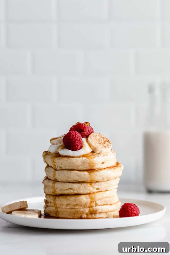 a stack of vegan oatmeal pancakes topped with raspberries and bananas