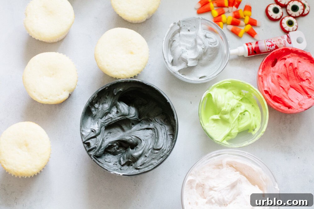 Various colors of frosting, decorations, and unfrosted cupcakes.