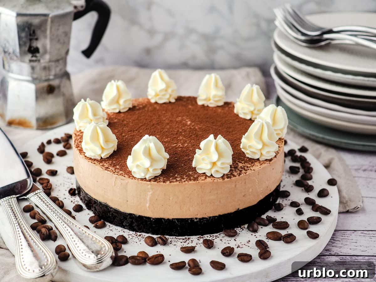 Coffee cheesecake on a serving board surrounded by coffee beans, with a stack of plates and forks and an espresso maker in the background.