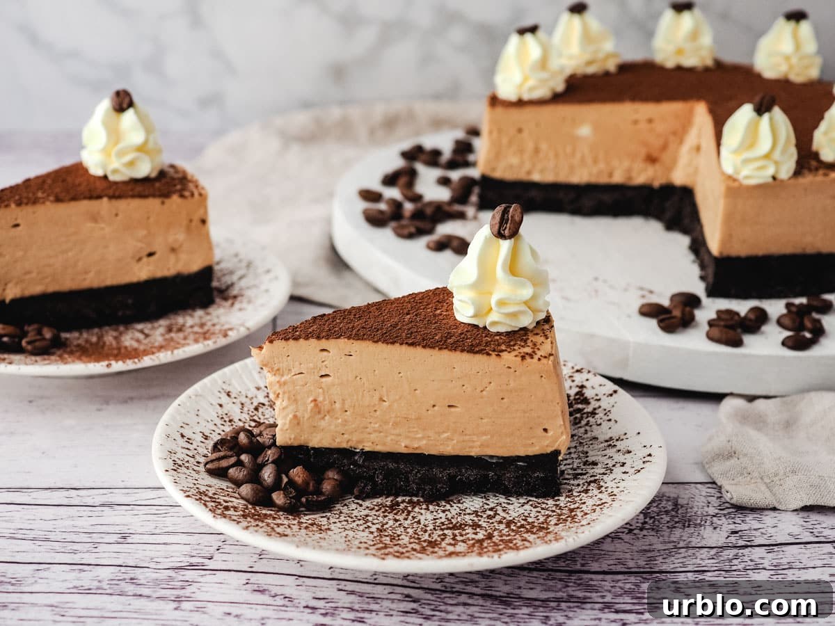 Slice of coffee cheesecake on a plate, with another slice on a plate and rest of cheesecake in the background.