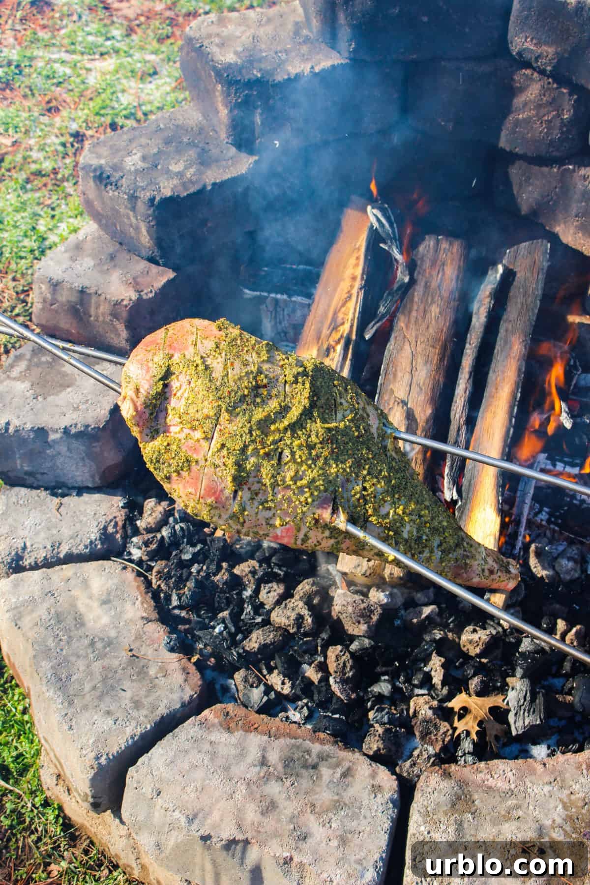 The lamb is roasted over the cooler side of the fire. 