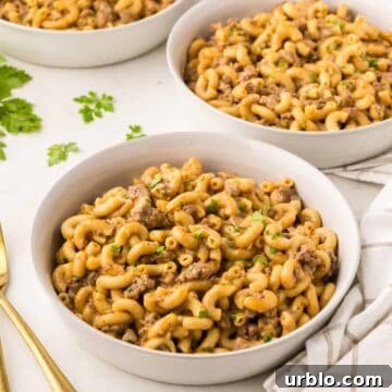 Pasta with ground beef in serving bowls with silverware and napkins.