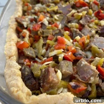 Diced beef with red peppers and green salsa in a tamale crust, all placed in a large glass dish.