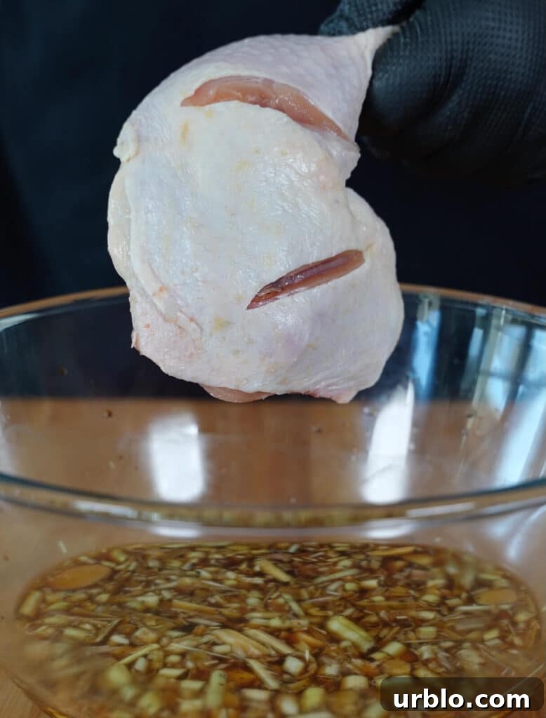 chicken quarter being placed into a bowl of marinade