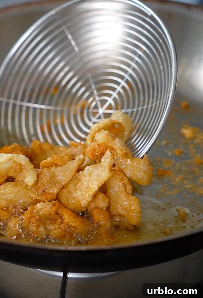 fried chicken pieces being scooped out of a frying pan