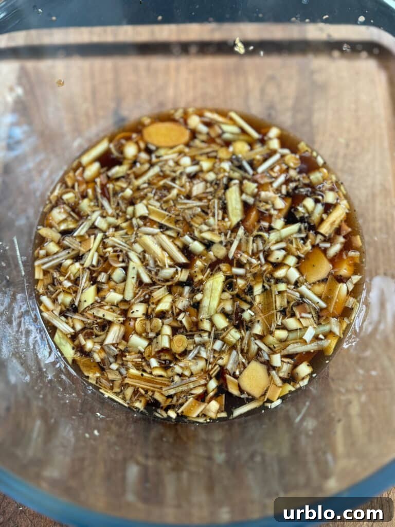 large glass bowl with chicken marinade in it with lemongrass, ginger, and garlic