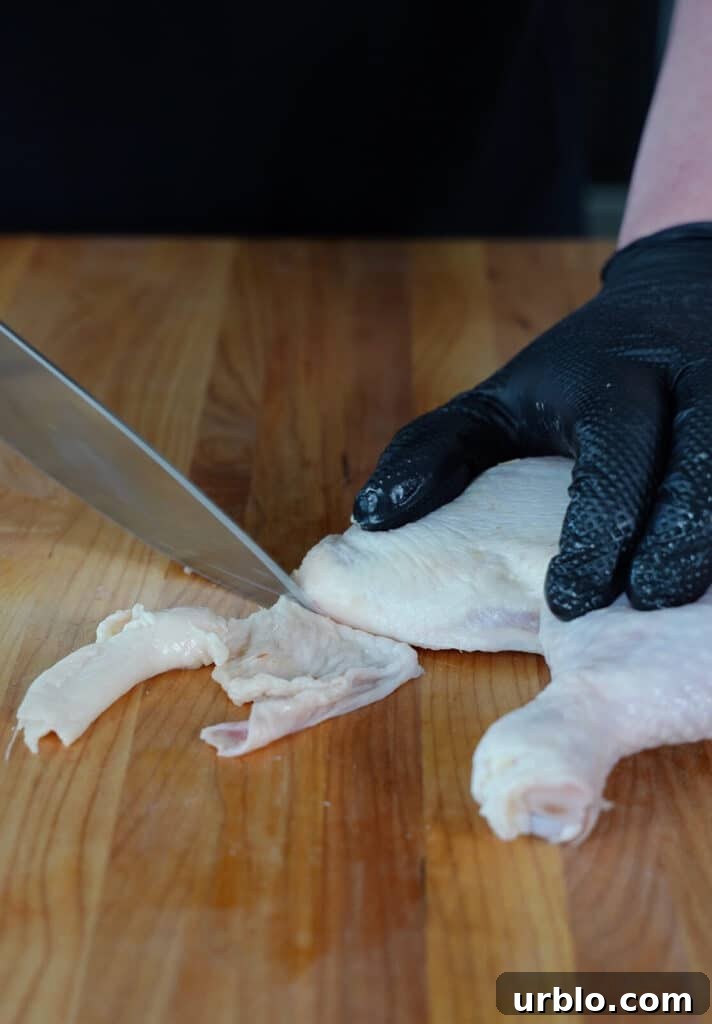 chicken skin being trimmed from a chicken thigh
