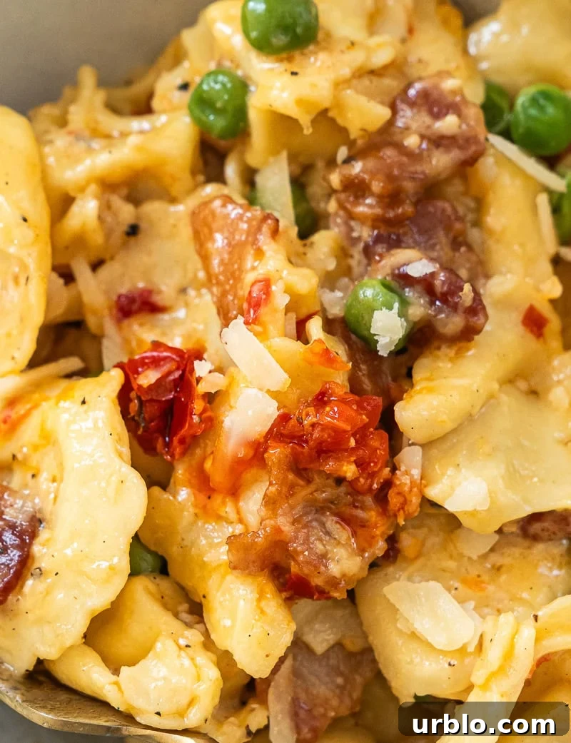 A closeup of cheese tortellini carbonara with bacon in glossy cream sauce
