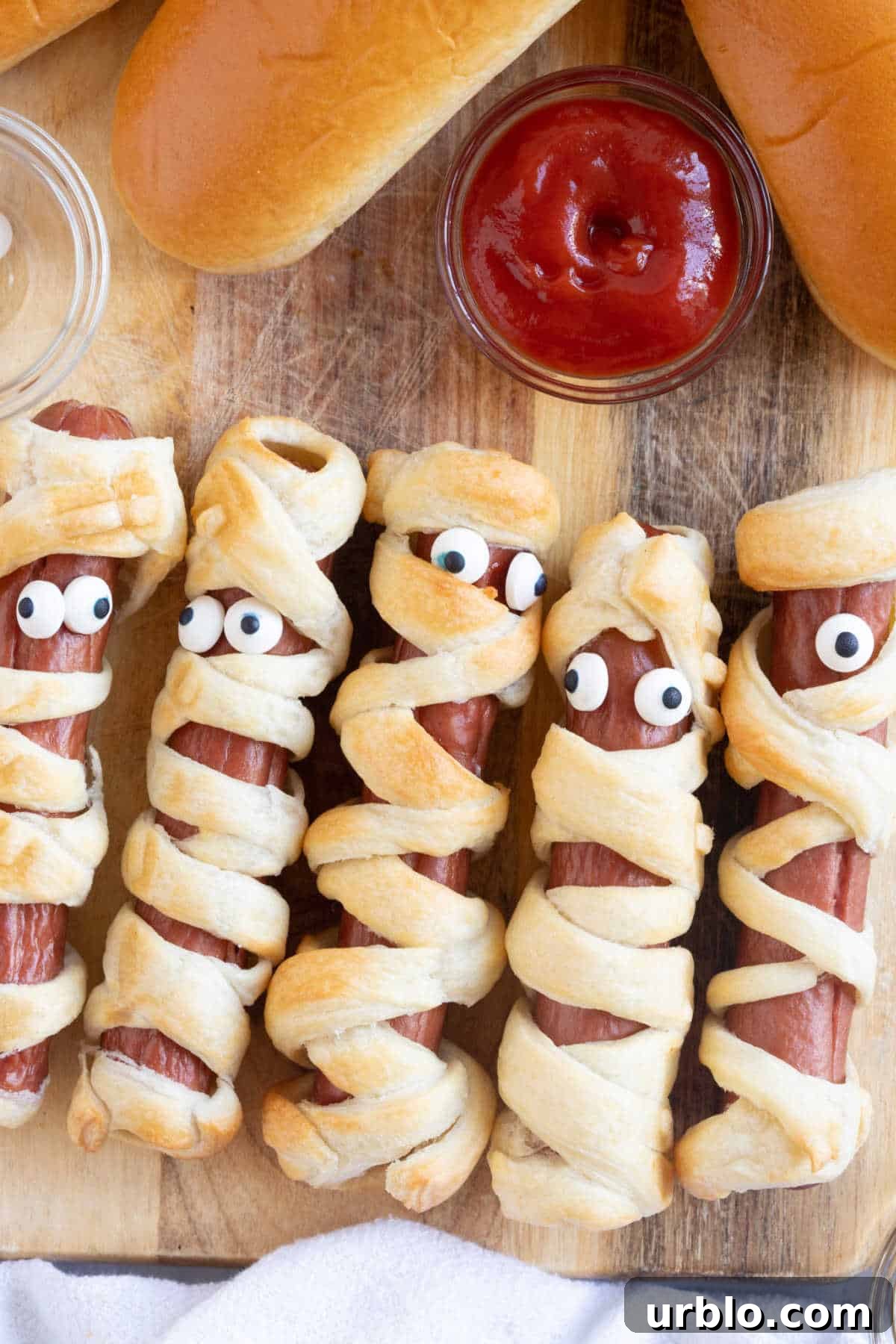 Air fryer mummy hot dogs on a wooden board.