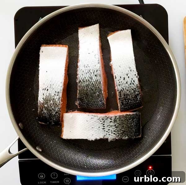 Placing salmon skin side up in a frying pan.