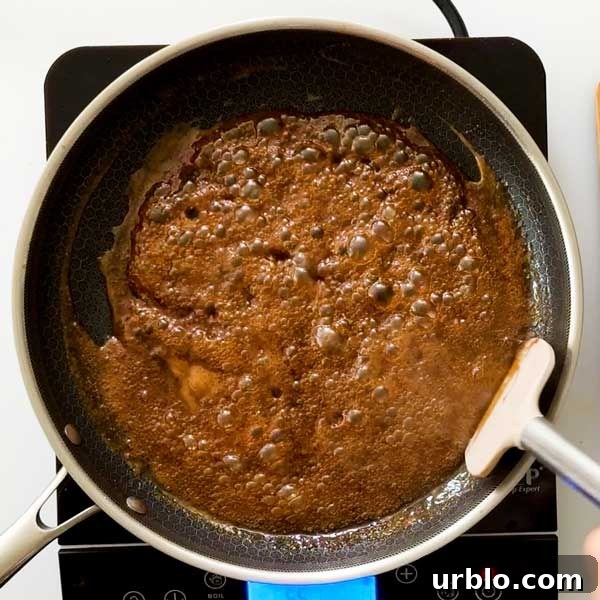 Thickening the honey garlic butter sauce in a frying pan.