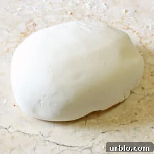 Very Hungry Caterpillar Birthday Cake Ideas and Decorating Tips 8 A disc of white homemade fondant on a marble surface.