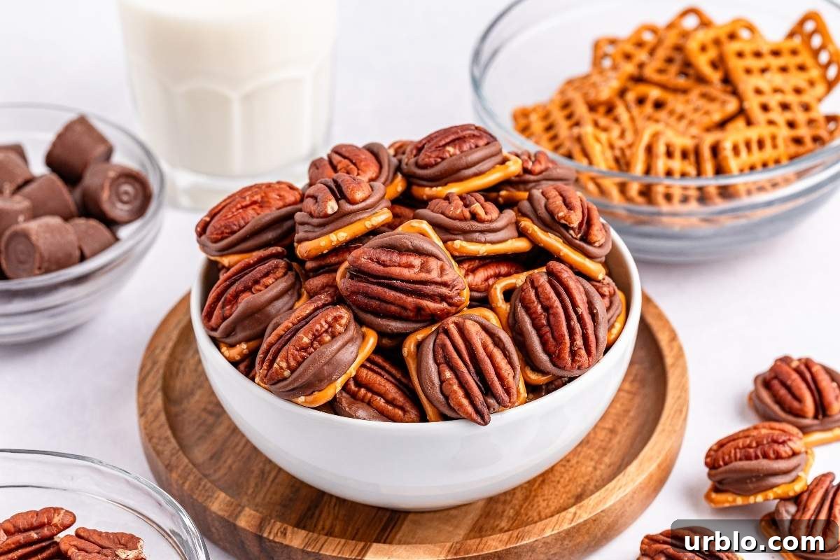 A white bowl filled delicious 3-ingredient pretzel turtle bites, sits on a wooden tray. Surrounding the bowl are dishes of pretzels, chocolate candies, and a glass of milk.