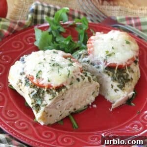 Crispy Baked Pesto Chicken Breast with Parmesan Crust 12 Baked pesto chicken with tomatoes and mozzarella cheese cut in half on on a red plate with arugula and a fork in background.