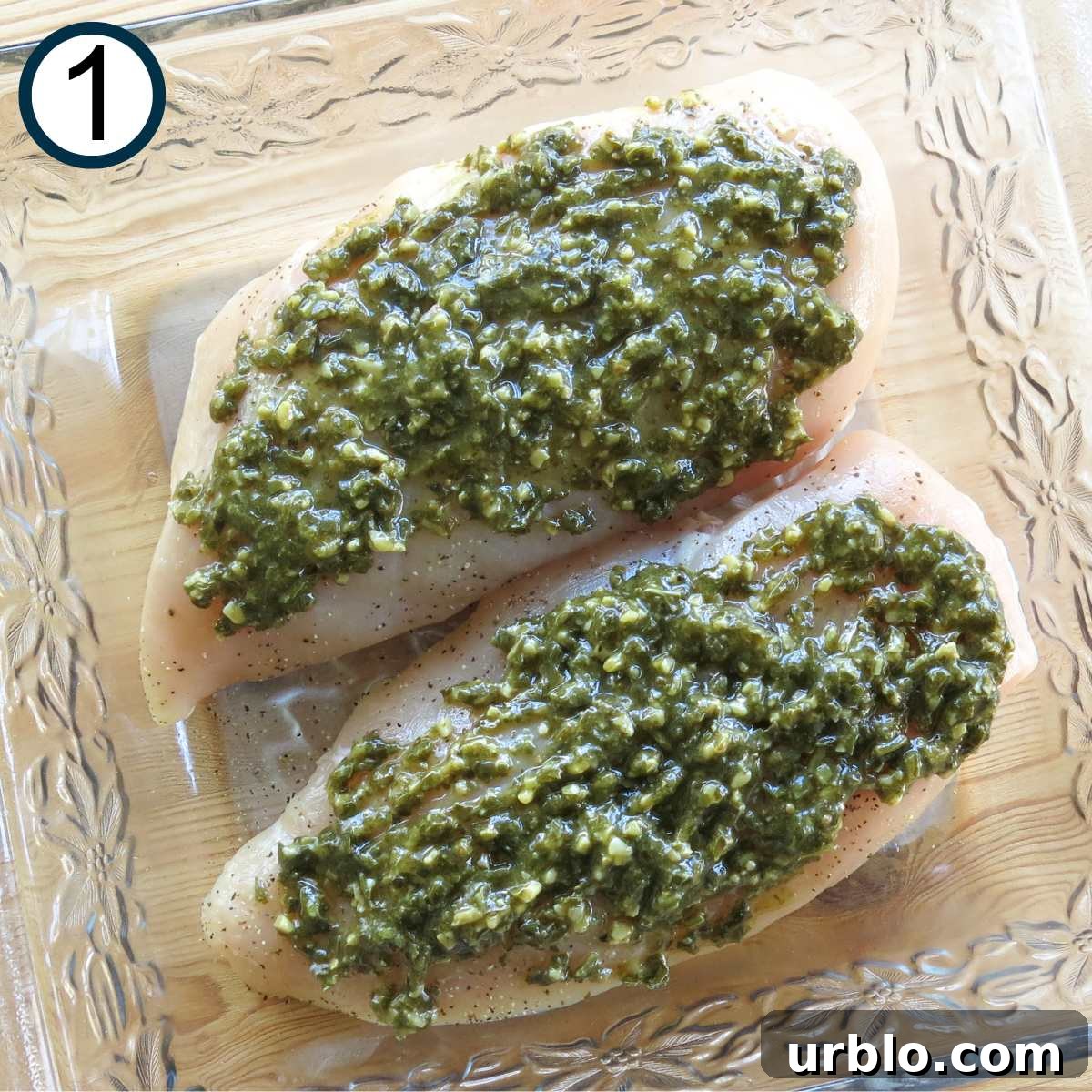 Crispy Baked Pesto Chicken Breast with Parmesan Crust 3 Two boneless skinless chicken breasts topped with pesto in a glass baking dish.