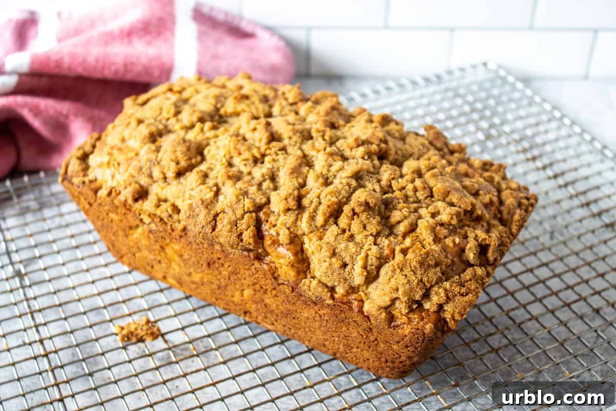 A loaf of bread topped with a crumble topping on a baking rack. 