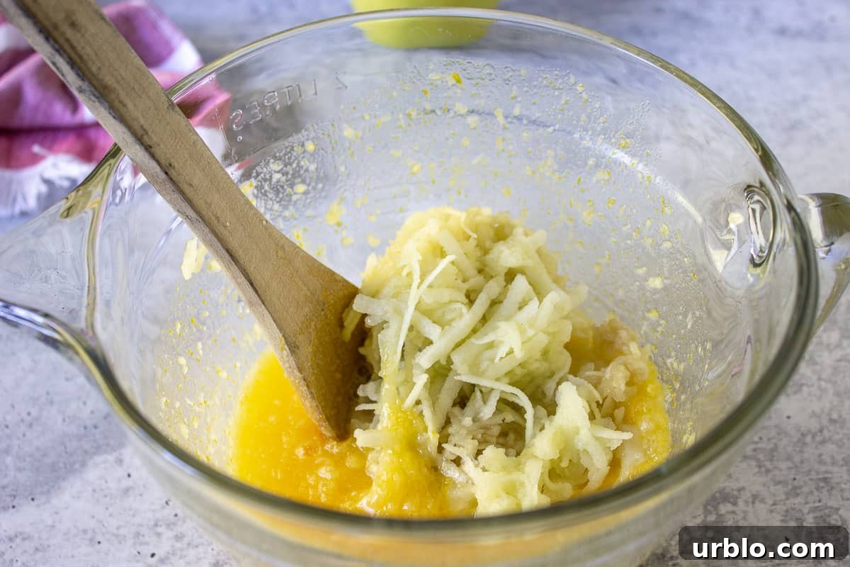 Eggs, butter and sugar combined together with grated apples on top of mixture.
