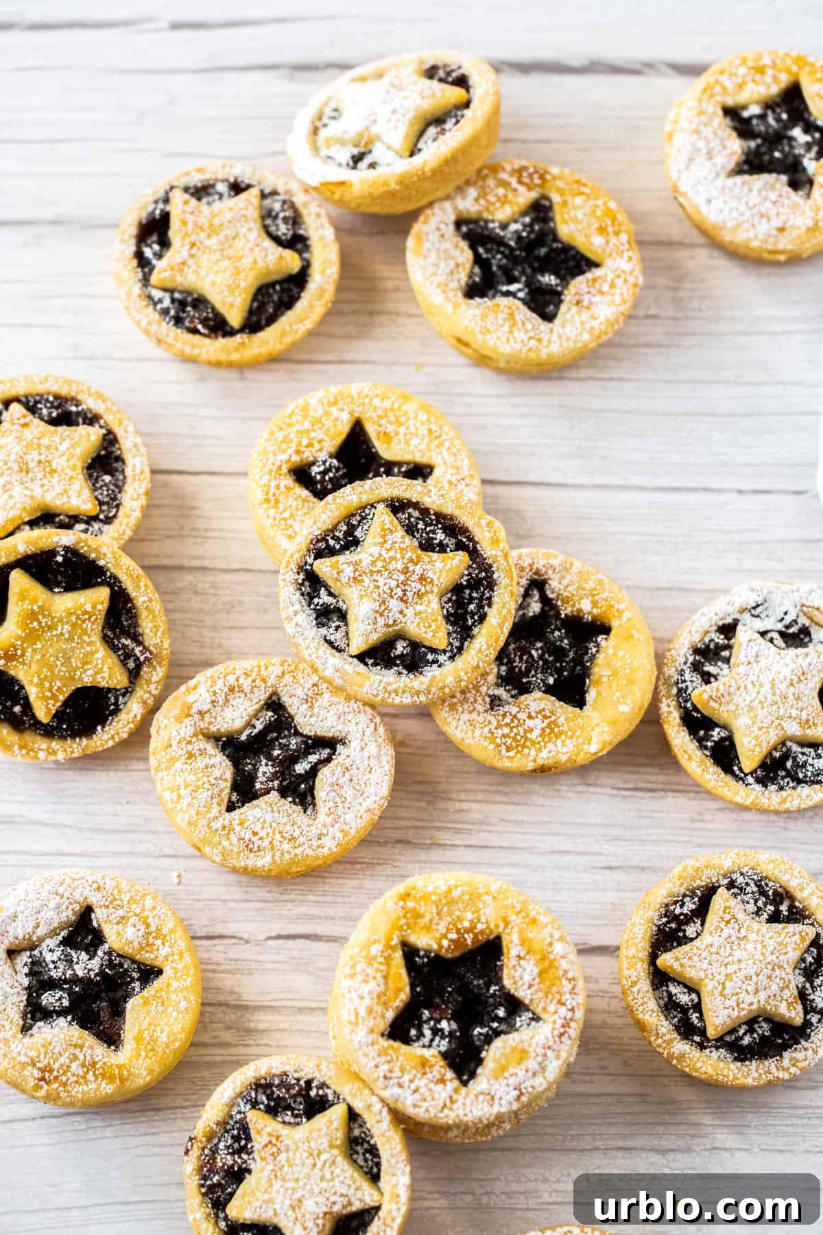 Mince pies dusted with icing sugar on a bench.