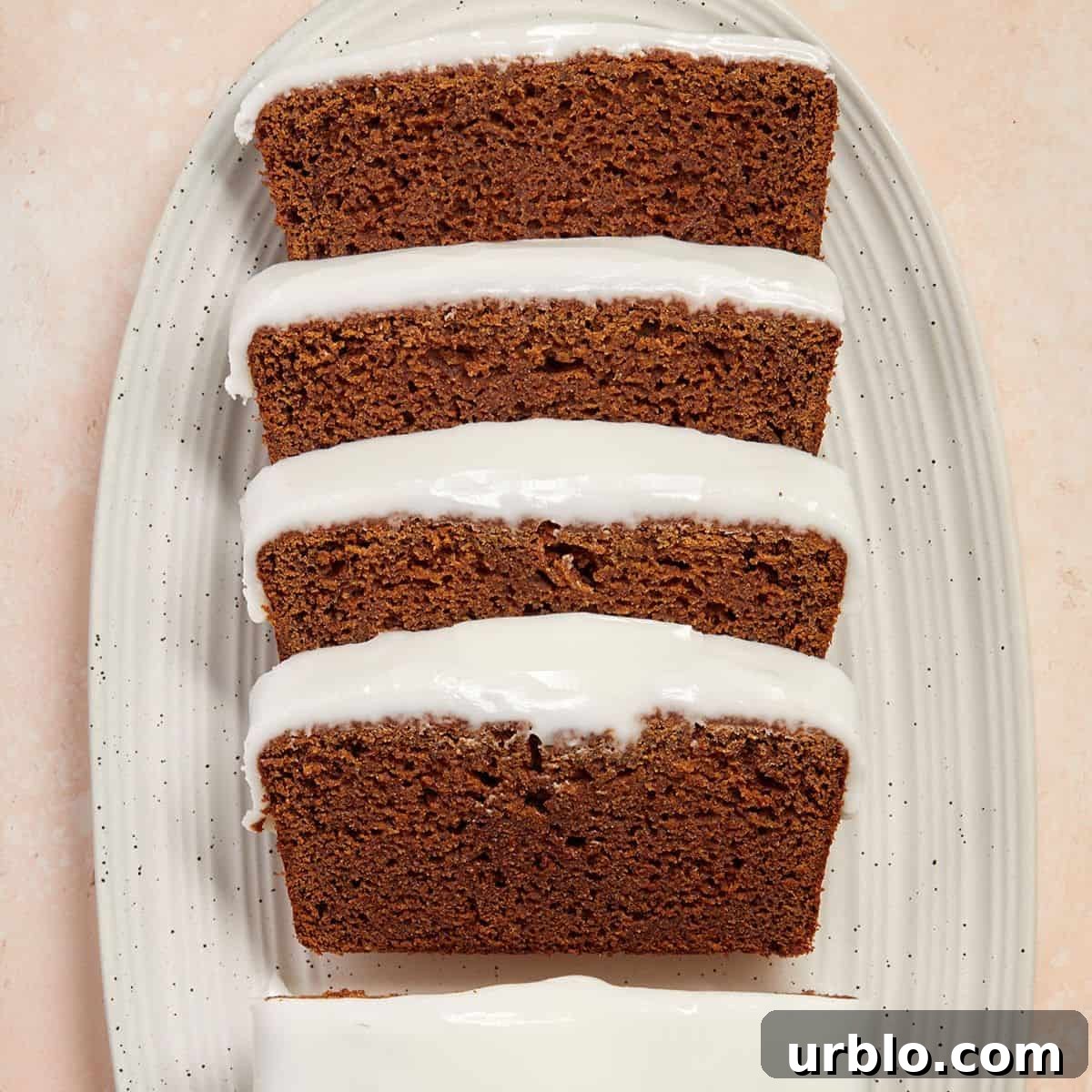 Slices of gingerbread loaf, sitting on a white oval dish.