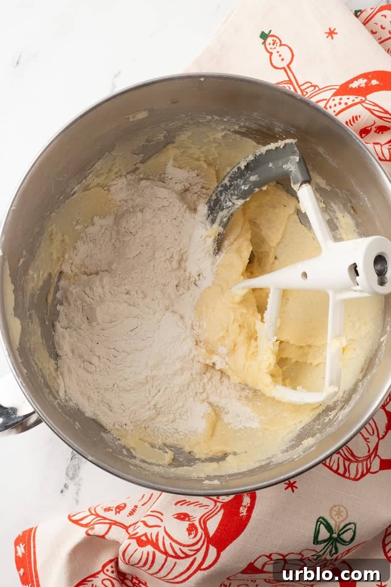 Chocolate-Dipped Pecan Sandies Cookies: Crunchy Butter Shortbread 6 Flour is added to the butter mixture in bowl from stand mixer.